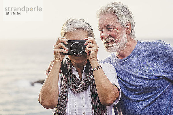 Ein reisendes älteres Ehepaar  das am Meer fotografiert