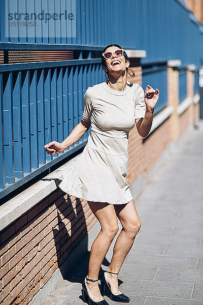 Fröhliche  modische junge Frau mit Kleid und Sonnenbrille