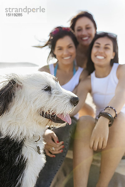 Glückliche Freundinnen mit Hund am Strand