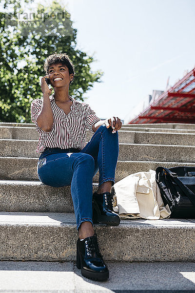 Geschäftsfrau mit Smartphone  die auf einer Treppe sitzt