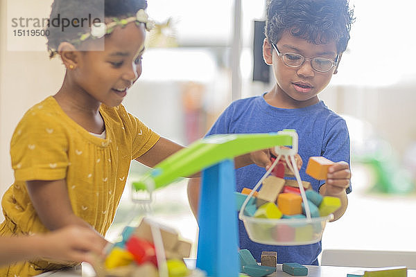 Junge und Mädchen spielen im Kindergarten mit Spielzeugwaagen