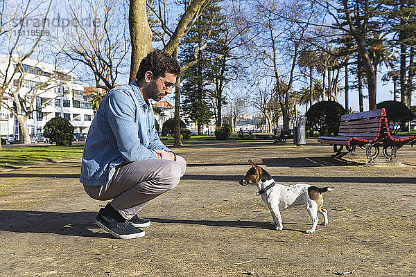 Junger Mann unterrichtet seinen Hund in einem Park