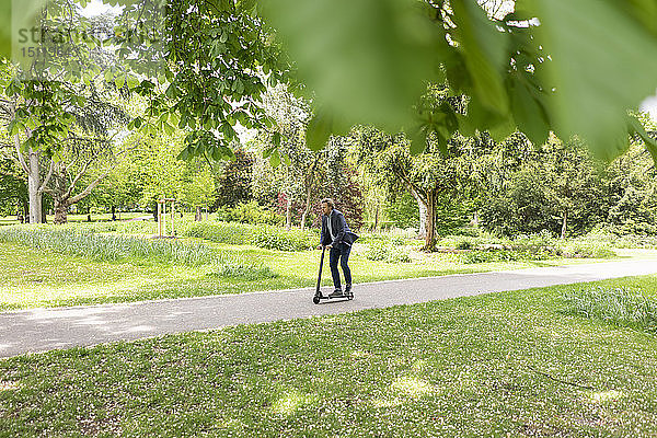 Geschäftsmann mit E-Scooter im Stadtpark