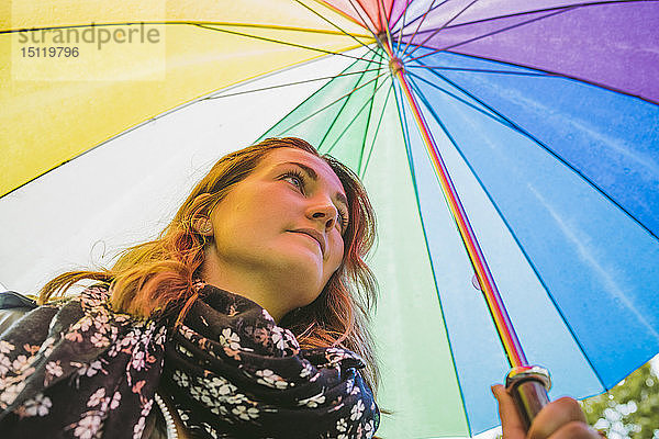 Junge Frau unter buntem Regenschirm