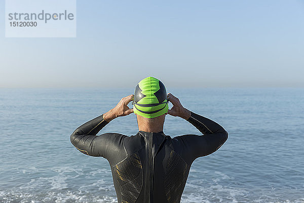 Triathlet  der sich zum Schwimmen vorbereitet  Schwimmkappe und Schutzbrille aufsetzen  Rückansicht