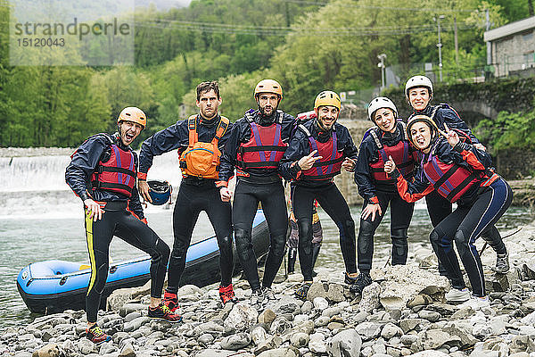 Gruppe spielerischer Freunde bei einem Rafting-Kurs  die am Boot posieren