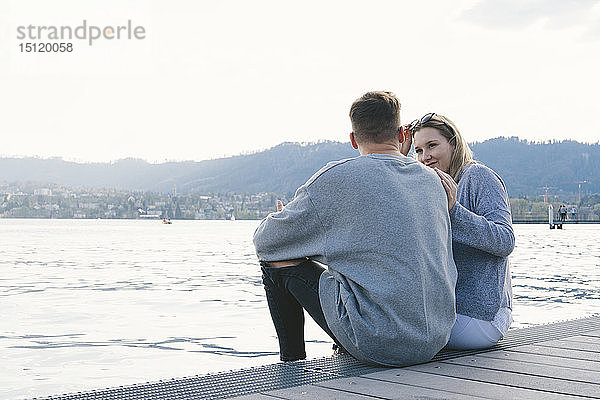 Junges Paar sitzt auf einem Steg am Zürichsee  Zürich  Schweiz