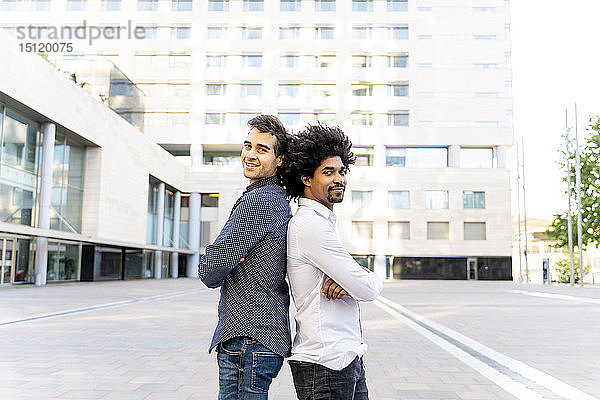 Porträt von zwei selbstbewussten Geschäftsleuten  die Rücken an Rücken in der Stadt stehen  Barcelona  Spanien