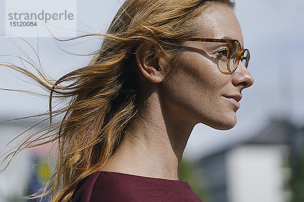 Profil einer jungen Frau mit Brille und windgepeitschtem Haar