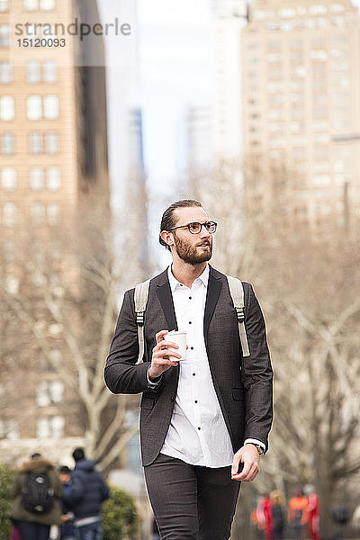 Porträt eines bärtigen jungen Geschäftsmannes mit Rucksack und Kaffee zum Mitnehmen  New York City  USA