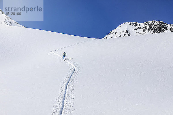 Österreich  Tirol  zwischen Ischgl und Galtür  Hohe Koepfe  Skitourengeher  der im Winter auf den Gipfel steigt