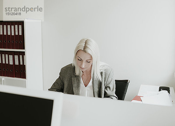 Junge Frau arbeitet am Schreibtisch im Büro