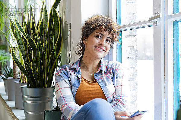 Porträt einer lächelnden Frau  die im Büro am Fenster sitzt