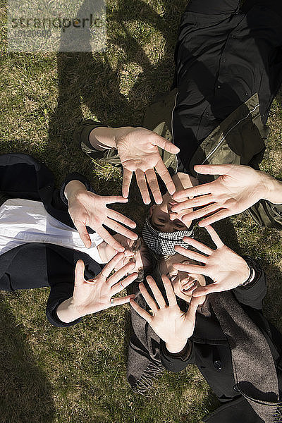 Gruppe junger Frauen  die im Gras liegen und mit ihren Händen einen Stern formen