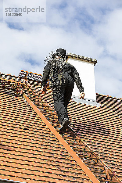 Schornsteinfeger klettert auf Hausdach
