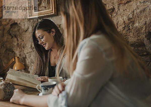 Zwei junge Frauen mit Buch in einem Cafe