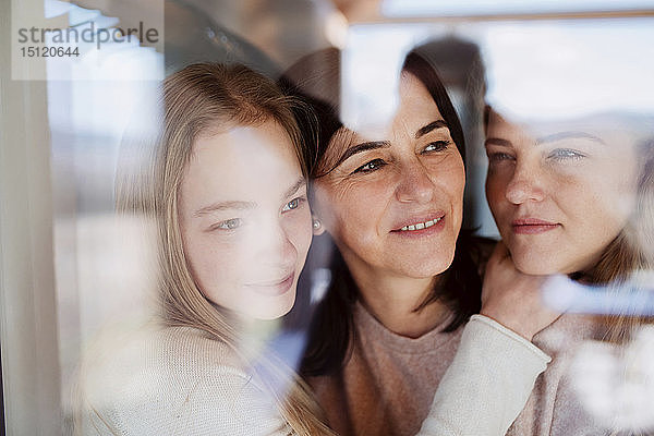 Besuchende Töchter  die ihre Mutter umarmen und am Fenster stehen