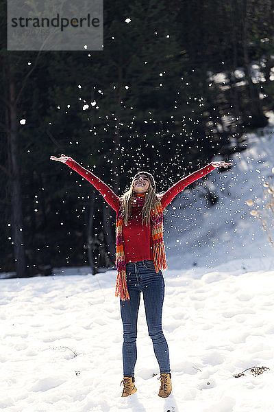 Junge blonde Frau wirft im Winter Schnee