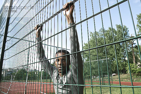 Porträt eines Sportlers hinter einem Zaun