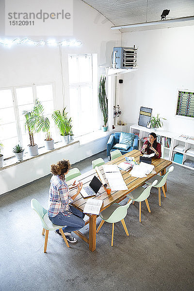 Zwei Frauen arbeiten am Tisch in einem modernen Büro