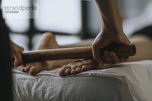 Nahaufnahme einer Massagetherapeutin mit einer Rolle auf den Fußsohlen einer Frau
