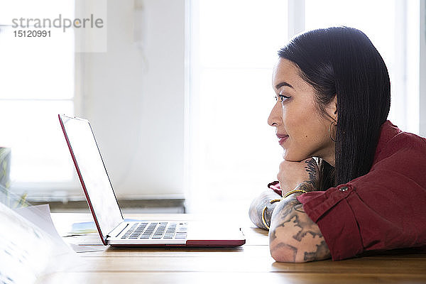 Frau benutzt Laptop am Tisch im Büro