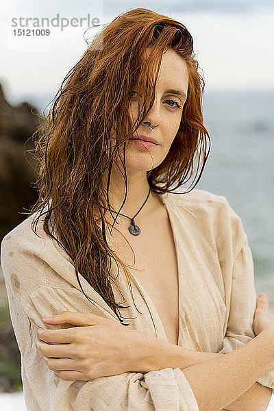 Porträt einer rothaarigen jungen Frau mit Nasenpiercing vor dem Meer