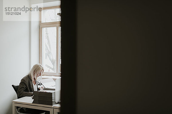 Junge Frau arbeitet am Schreibtisch im Büro