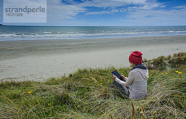 Frau mit Tablette am Strand von Foxton  Küste von Kapiti  Nordinsel  Neuseeland