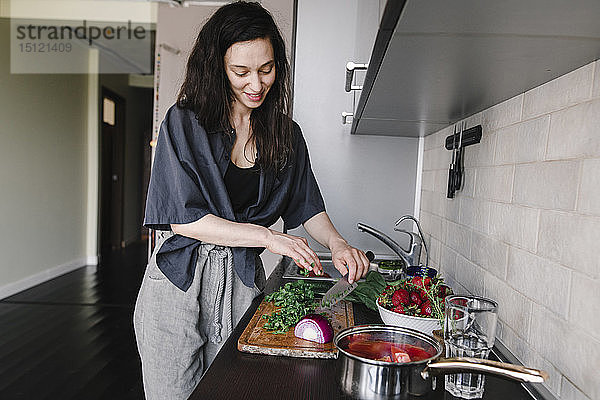 Lächelnde Frau bereitet in der Küche Salat zu