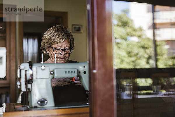 Ältere Frau benutzt zu Hause eine alte Nähmaschine