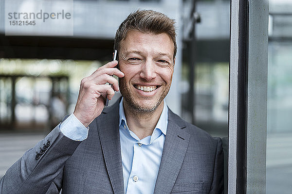 Porträt eines glücklichen Geschäftsmannes am Handy im Freien