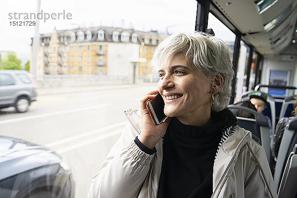 Frau sitzt im Bus und spricht mit dem Smartphone