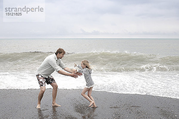 Vater spielt mit seiner Tochter am Strand