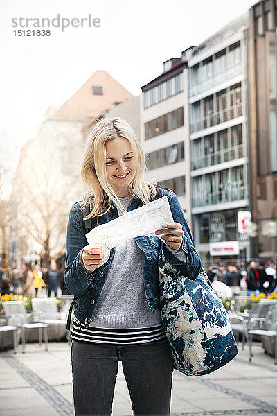 Porträt einer lächelnden blonden Frau beim Blick auf den Stadtplan  München  Deutschland