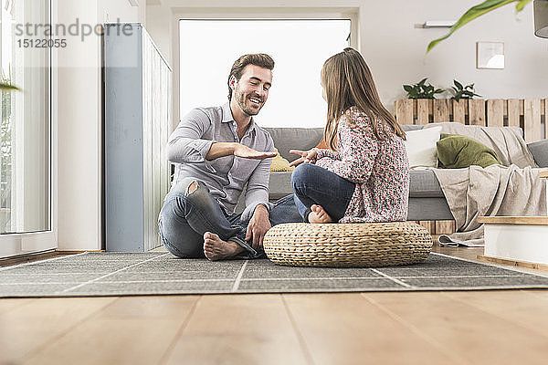 Junger Mann und kleines Mädchen sitzen zu Hause und spielen Papier  Schere  Stein