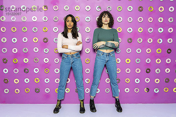 Zwei junge Frauen posieren in einem Indoor-Themenpark mit Donuts an der Wand