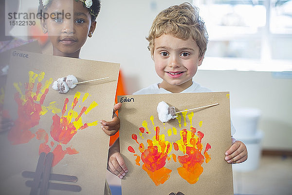 Porträt von lächelnden Kindern  die Bilder von Feuer im Kindergarten präsentieren