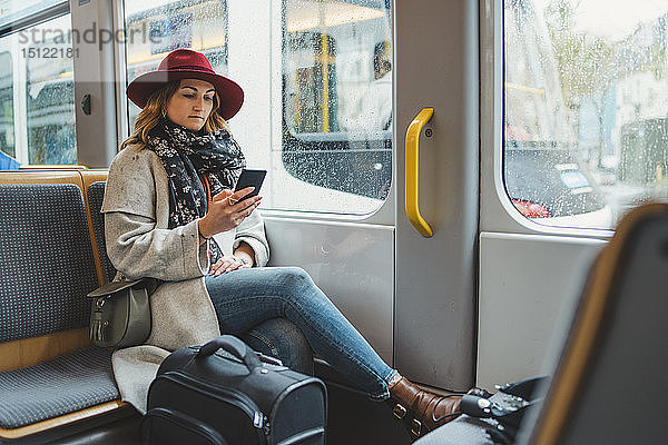 Junge Frau benutzt Handy in einer Straßenbahn