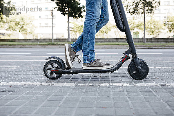 Beine des auf dem E-Scooter stehenden Mannes