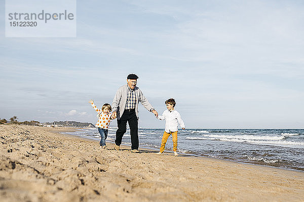 Großvater amüsiert sich mit seinen Enkelkindern am Strand