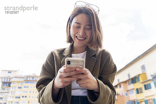 Italien  Florenz  glückliche junge Frau  die in der Stadt mobil telefoniert
