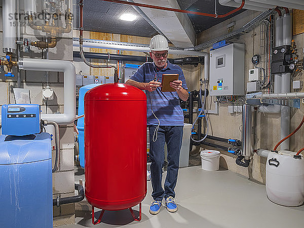 Leitender Handwerker prüft Wasseraufbereitungsanlage  Lesetablette