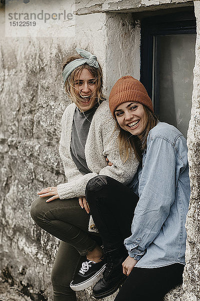 UK  Schottland  zwei lachende junge Frauen an einem Gebäude