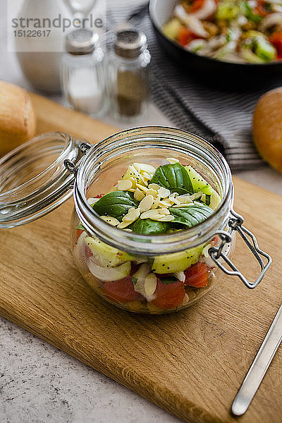 Glas Salat mit Gurken  Kichererbsen  Zwiebeln  Kirschtomaten  Basilikum  Chiasamen und Mandelsplittern