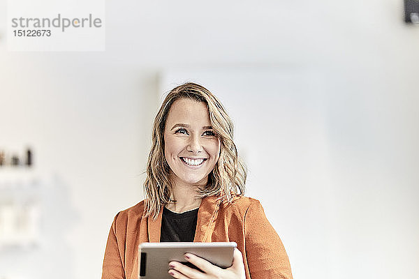 Porträt einer lächelnden jungen Geschäftsfrau mit Mini-Tablette