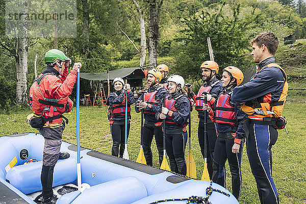 Ausbilder im Gespräch mit einer Gruppe von Freunden bei einem Rafting-Kurs