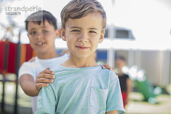 Porträt eines lächelnden Jungen mit Freunden auf einem Spielplatz im Kindergarten