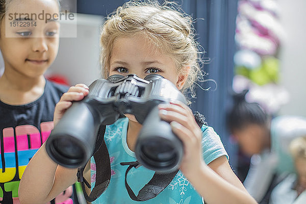 Mädchen hält Fernglas im Kindergarten