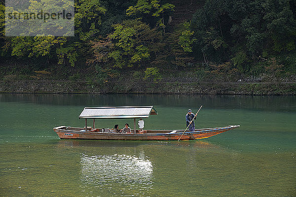 Touristen beim Sightseeing in einem kleinen Holzboot auf dem Fluss Oi in der Region Arashimaya außerhalb von Kyoto  Japan  Asien